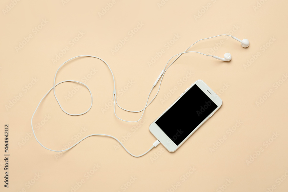 Mobile phone and earphones on beige background