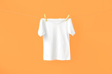 White T-shirt Hanging On Rope Against Color Background