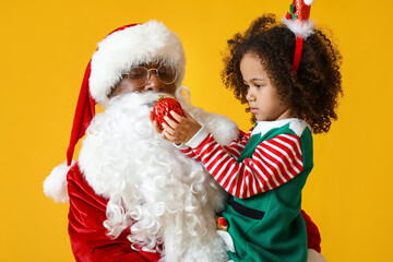 Sticker - Little African-American girl with Santa Claus and Christmas ball on yellow background