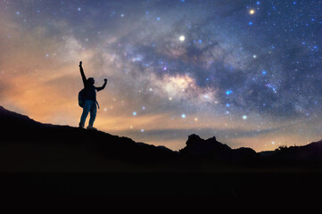 Wall Mural - Landscape with Milky Way. Night sky with stars and silhouette of a standing happy man on the mountain, Success or winner, leader concept. High iso with Noise.