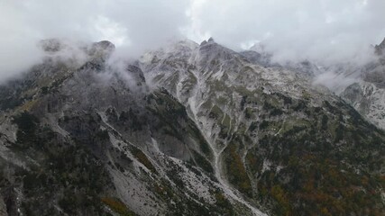 Wall Mural - High peak of mountain covered in misty fog on a cloudy Autumn day in Albanian Alps