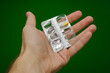 blister pack with one pill in hand on green background