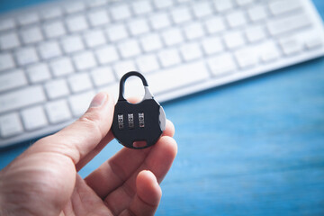  Hand holding padlock over computer keyboard.