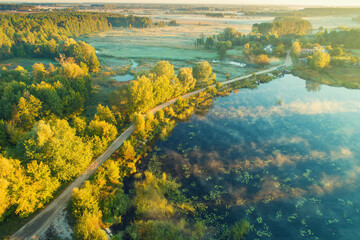 Wall Mural - Dirt road along the lake in the early morning. View from above