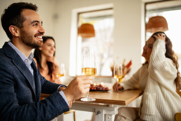 Wall Mural - Cropped portrait of smiling man drinking white wine, having cheerful meeting with friends at cafe on warm sunny day