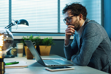 Wall Mural - Young businessman sitting at desk and thinking