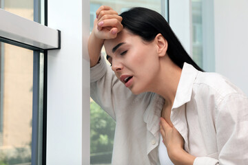 Canvas Print - Young woman suffering from breathing problem near window indoors