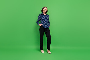 Full size photo of nice elder manager lady wear shirt trousers stilettos isolated on green color background