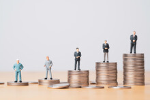 Different Miniature Businessman Standing On Different Height Coins Stacking , Inequality Income And Salary In Each Position In Company Concept.