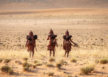 Group Of Women Of The Himba Tribe Are Walking Through The Desert In National Clothes.