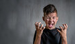 © Ermolaeva Olga - Teen boy screaming in anger on dark background
