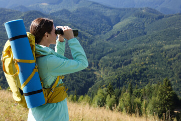 Sticker - Tourist with hiking equipment looking through binoculars in mountains