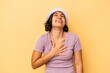 © Asier - Young latin woman isolated on yellow background laughs out loudly keeping hand on chest.