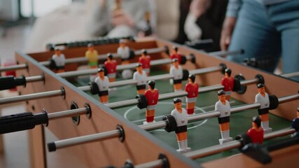 Wall Mural - Close up of colleagues playing at foosball table after work. Workmates using board to play football and to score goal while enjoying drinks and snacks at celebration after hours