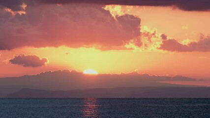 Wall Mural - Stunning dramatic, cloudy sunrise with a bright sun rising over a calm water. Natural background, Sardinia, Italy.