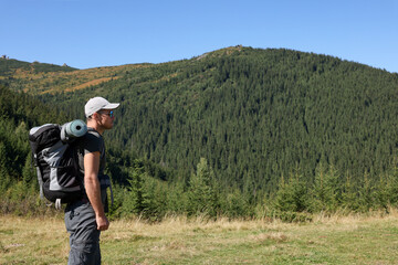 Wall Mural - Man with backpack and sleeping mat in mountains. Space for text