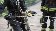 Fireman Tests Rope And Pulley Before Descending From Bridge, Medium Slow Motion Shot