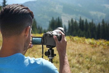 Sticker - Man taking photo of nature with modern camera on stand outdoors