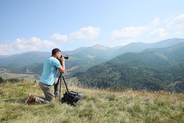 Wall Mural - Professional photographer taking picture with modern camera in mountains. Space for text