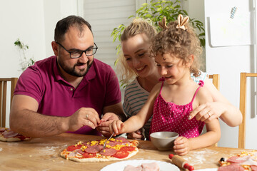 the happy young family are cooking homemade pizza