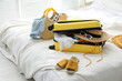 © New Africa - Open suitcase full of clothes, shoes and summer accessories on bed in room