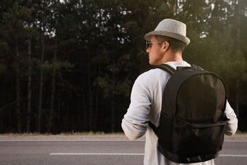 Wall Mural - Man with backpack on road near forest