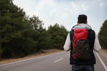 Poster - Man with backpack on road near forest, back view