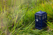 Police Public Call Box On Green Grass. Blue Police Box From London As Doctor Who Tardis. Time And Space Machine In Miniature. Time Travel.