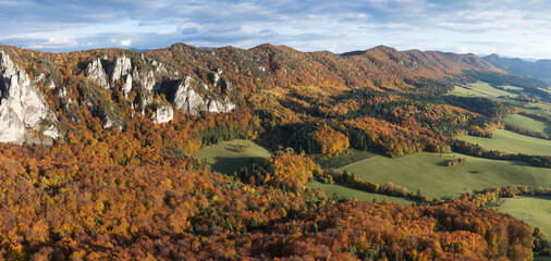 Wall Mural - Scenic landscape in Sulov, Slovakia, on beautiful autumn sunrise with colorful leaves on trees in forest and bizarre pointy rocks on mountains and slight mist in the valleys and dramatic clouds on sky