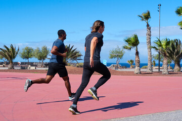 Two attractive confident young healthy sportsmen running outdoors at the beach