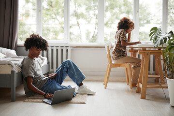 Wall Mural - Side view portrait of African-American brother and sister studying at home together, copy space