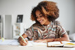 Front view portrait of female African-American student enjoying homework and smiling, copy space
