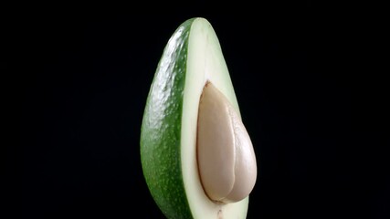 Wall Mural - Footage of rotating avocado half on black background