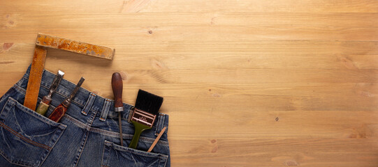 Canvas Print - Kit of woodwork tool in jeans pocket at wooden table background. Woodworking concept