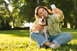 © InsideCreativeHouse - Young caucasian woman student female pet owner taking selfie photo image on smart phone, having video call conversation with dog jack russell terrier online in park
