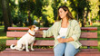 © InsideCreativeHouse - Pet adoption care. Young caucasian woman student pet owner playing walking her dog jack russell terrier while drinking coffee relaxing in park outdoors.