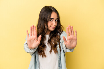 Young caucasian woman isolated on yellow background standing with outstretched hand showing stop sign, preventing you.