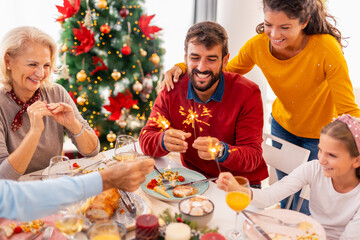 Family holding sparklers while having Christmas dinner