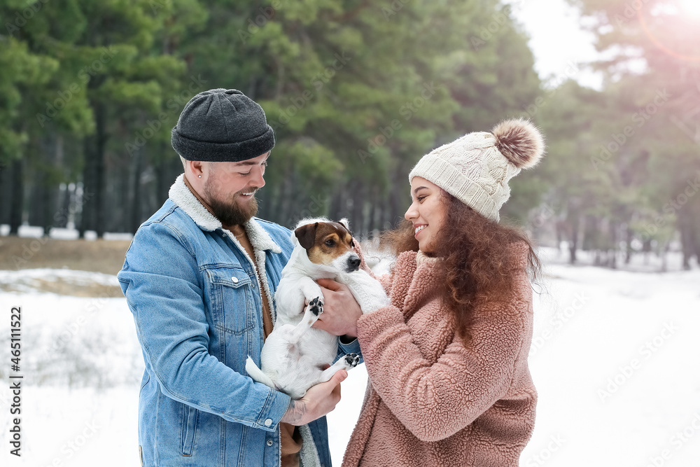 Happy young couple with dog in forest on winter day