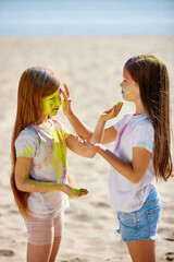 child girls smeared with colored powder celebrate holi festival.