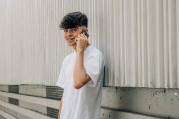 Canvas Print - portrait teenager boy talking on mobile phone on street wall