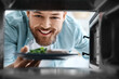 © Pixel-Shot - Young man putting plate with food into microwave oven, view from inside