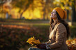 © Alliance - smiling 40 years old woman in brown coat and hat sitting