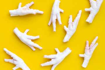 Wall Mural - Raw chicken feet on yellow background.