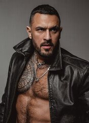 Fashion style portrait of handsome guy. Fashion brutal guy with sexy naked torso in leather jacket.