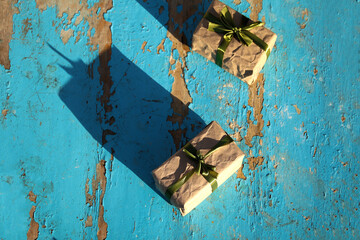 Two, 2 wrapped vintage gift boxes with olive silk ribbon bow on blue (turquoise) old wooden background. Present box in craft paper with green bow with shadow. Holiday concept. Top view