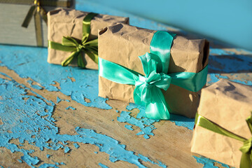 Cropped four, 4 wrapped vintage gift boxes with olive silk ribbon bow on blue (turquoise) old wooden background. Present box in craft paper with green bow with shadow. Holiday concept