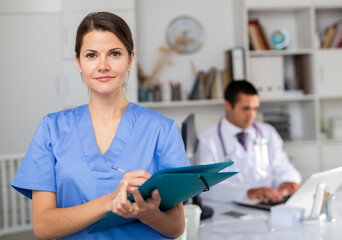 Wall Mural - Positive nurse with folder of documents at clinic office