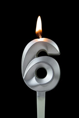 Burning silver birthday candle isolated on black background, number 6