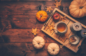 Hot tea with cookies, apple and fall foliage and pumpkins on wooden background